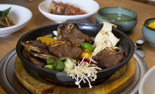 LA갈비 철판 — 새송이·피망·팽이버섯·대파, 뒤로 녹차물 그릇과 반찬